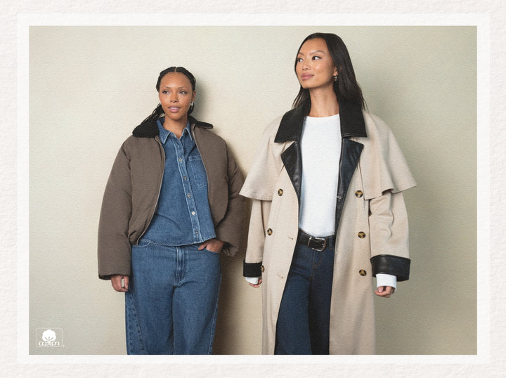 Two women wearing coats and jeans against a plain background
