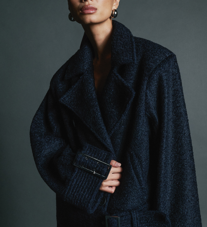 Person wearing a dark blue coat against a gray background